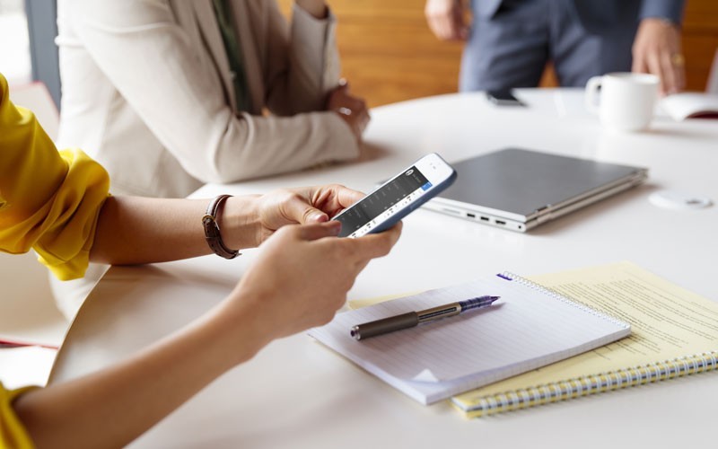 Enable workplace productivity with HPE software solutions Woman in meeting working on mobile device