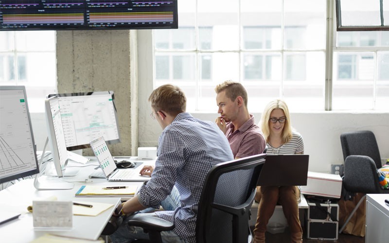 Build your cloud environment Coworkers collaborating in open office using desktop and laptop devices