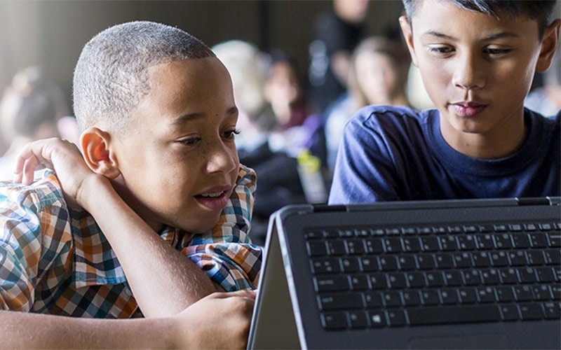Discover the innovative community partnership programme Two young students working on a HP device