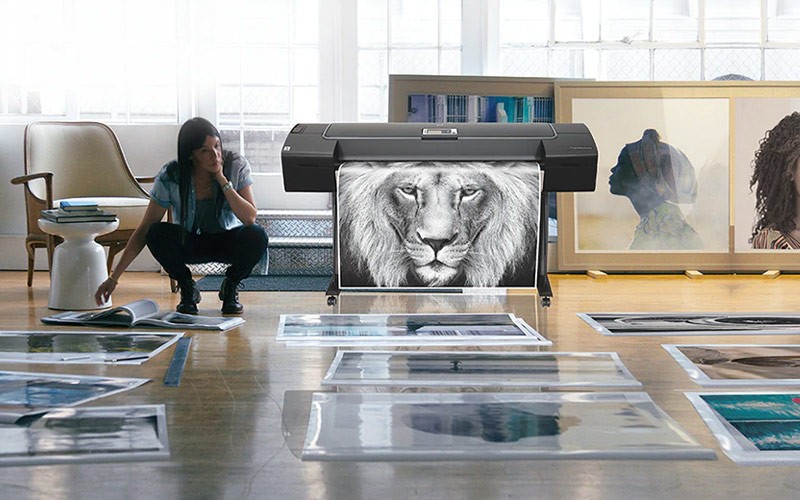 Allows you to print on different paper types and sizes with no manual switching required. Woman reviewing prints from a DesignJet printer