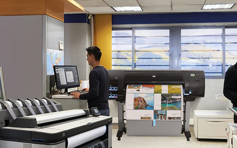 Efficiently produce high-quality posters, photos, indoor signs, line drawings, maps and more. Man working in a printing room