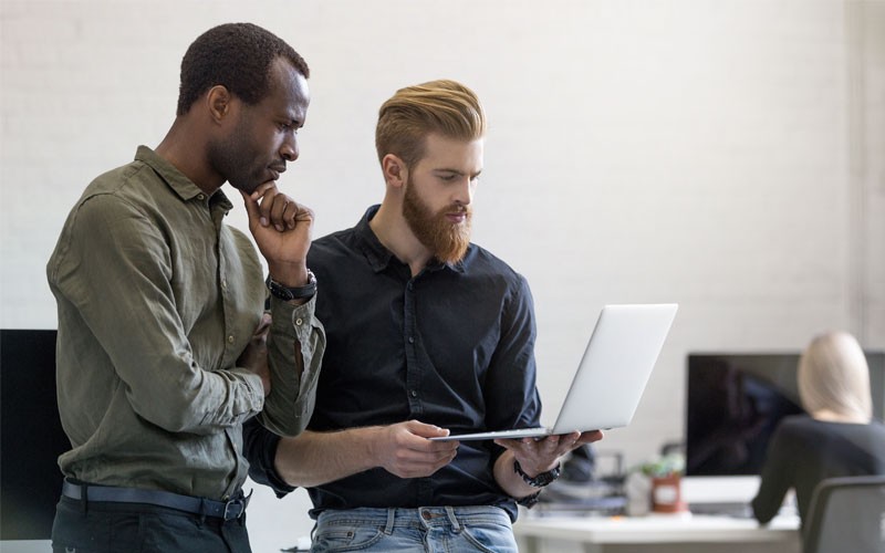 JBoss EAP reduces the time it takes to scale Two standing businessmen collaborate with laptop computer