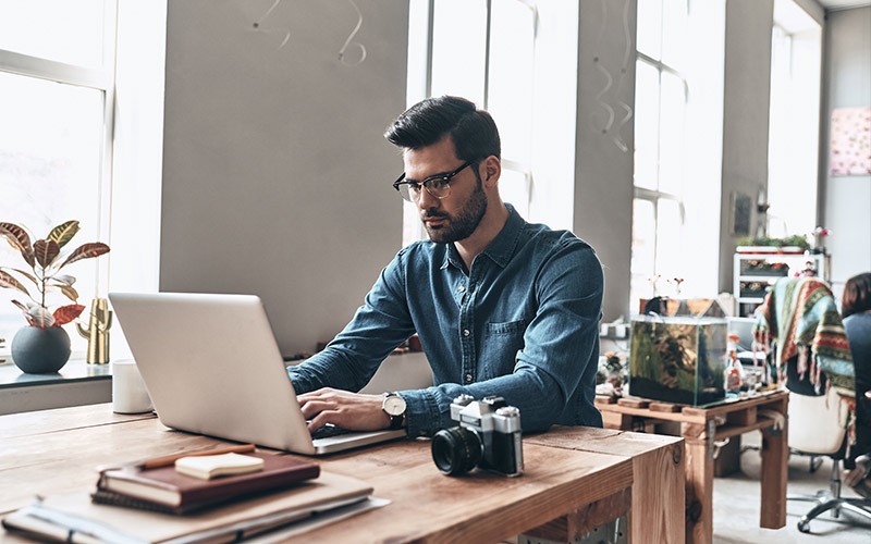 Unify the management f software assets Casually dressed man working on a laptop