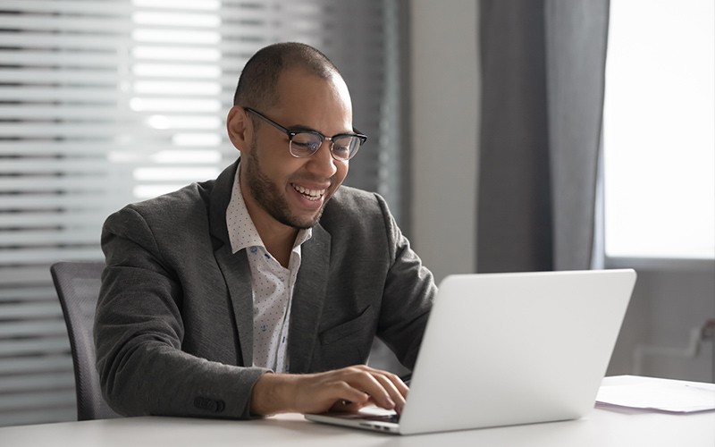 Manage software licenses more effectively Business man smiling while working on a laptop