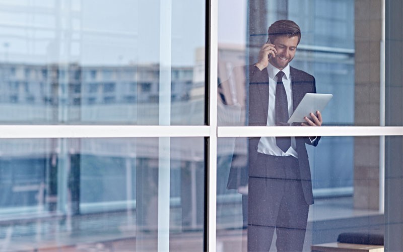 Transform your organisation with IT today Business man on mobile phone while holding tablet device
