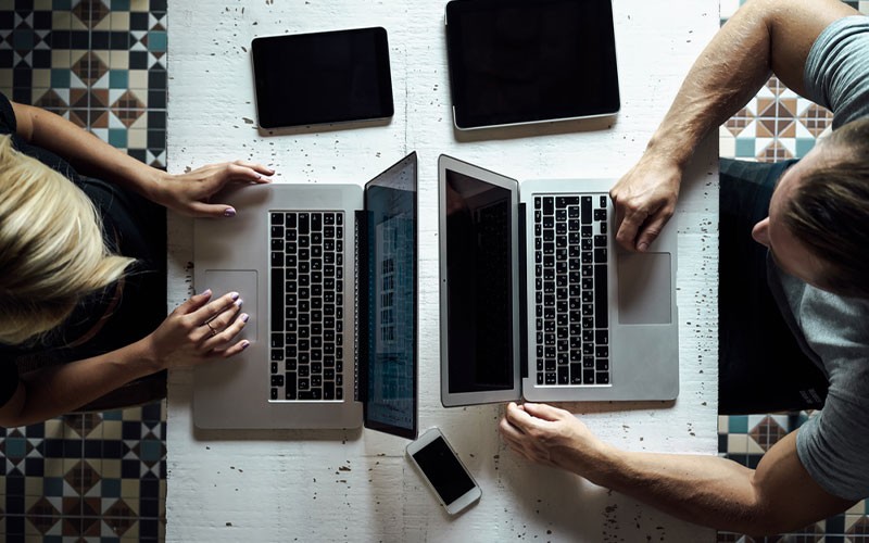 Remote working solutions Two colleagues using laptops on a desk