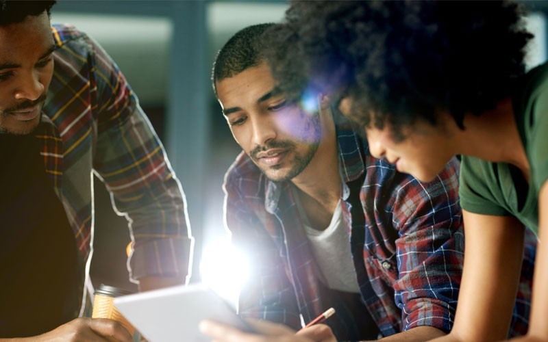 By unifying endpoint management and enabling secure mobile access Three individuals looking over tablet