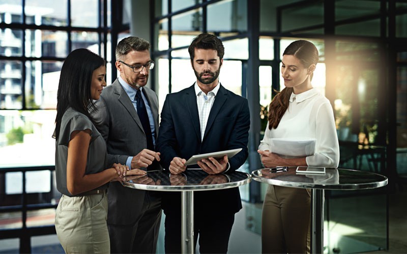 Hyper converged infrastructure and security solutions Group of employees looking over tablet at high table