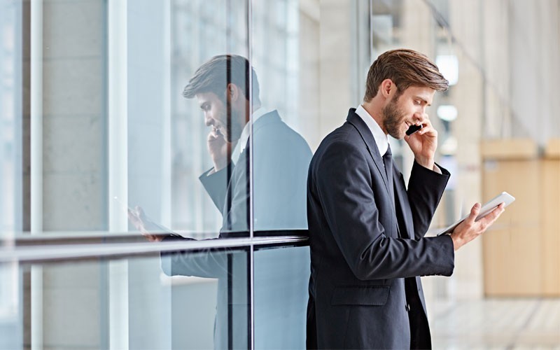 Mobile workforce and secure devices Business man outside building using mobile phone and tablet