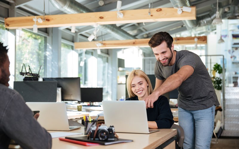 VMware vRealize Suite to form a multivendor hybrid cloud platform Two employees helping each other with laptop device