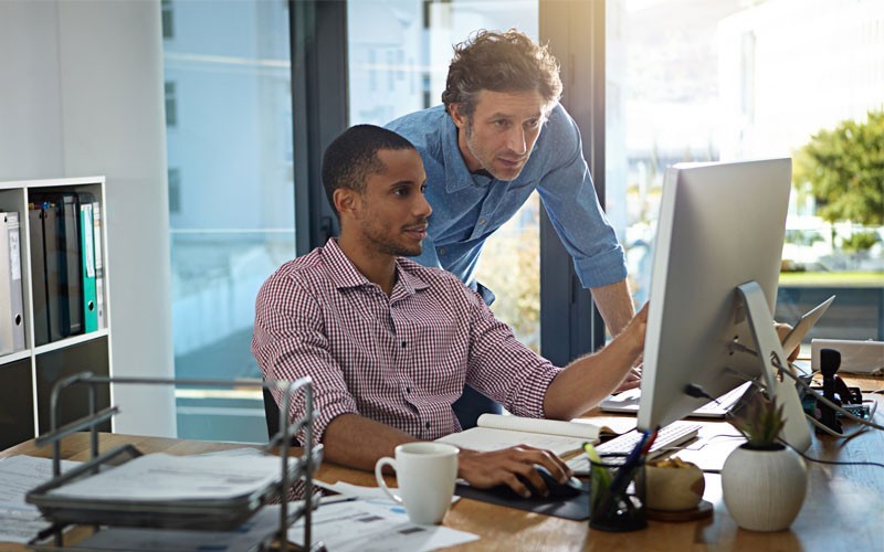 Workspace ONE and Office 365 blend together seamlessly Two male employees looking at desktop