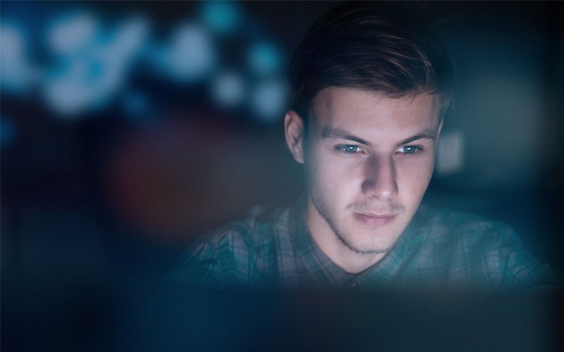 VMware vRealize Network Insight provides intelligent operations that help secure network infrastructures Male user looking at monitor at night
